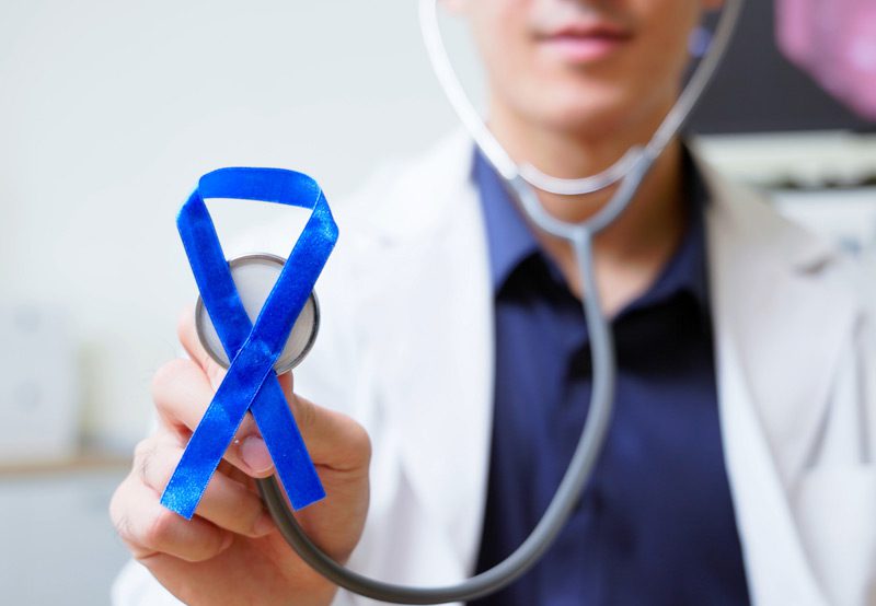 Close-up-of-male-doctor-holding-stethoscope-with-blue-ribbon Close-up-of-male-doctor-holding-stethoscope-with-blue-ribbon