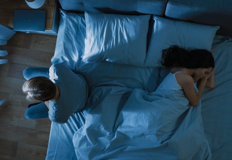 Couple-sitting-apart-on-bed,-illustrating-intimacy-issues-related-to-HSDD