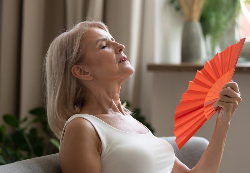 Woman-experiencing-a-hot-flash-using-a-fan-for-relief