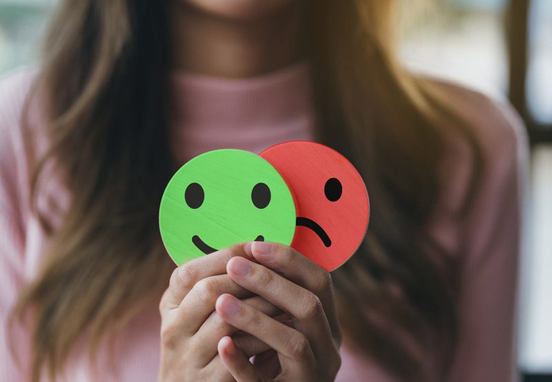 Woman-holding-smiley-face-reflecting-mental-health-concept