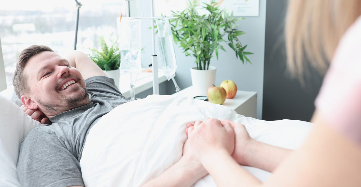 Smiling man lies on hospital bed