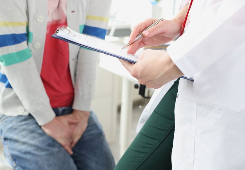 Man-sitting-at-doctor-appointment-and-holding-on-to-genital-area