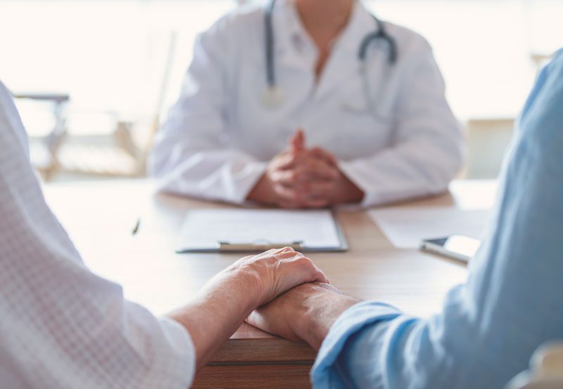 Mature-couple-holding-hands-during-a-medical-consultation-with-a-urology-specialist