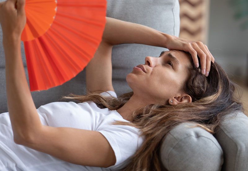 Woman-fanning-herself-to-relieve-menopausal-hot-flashes Woman-fanning-herself-to-relieve-menopausal-hot-flashes